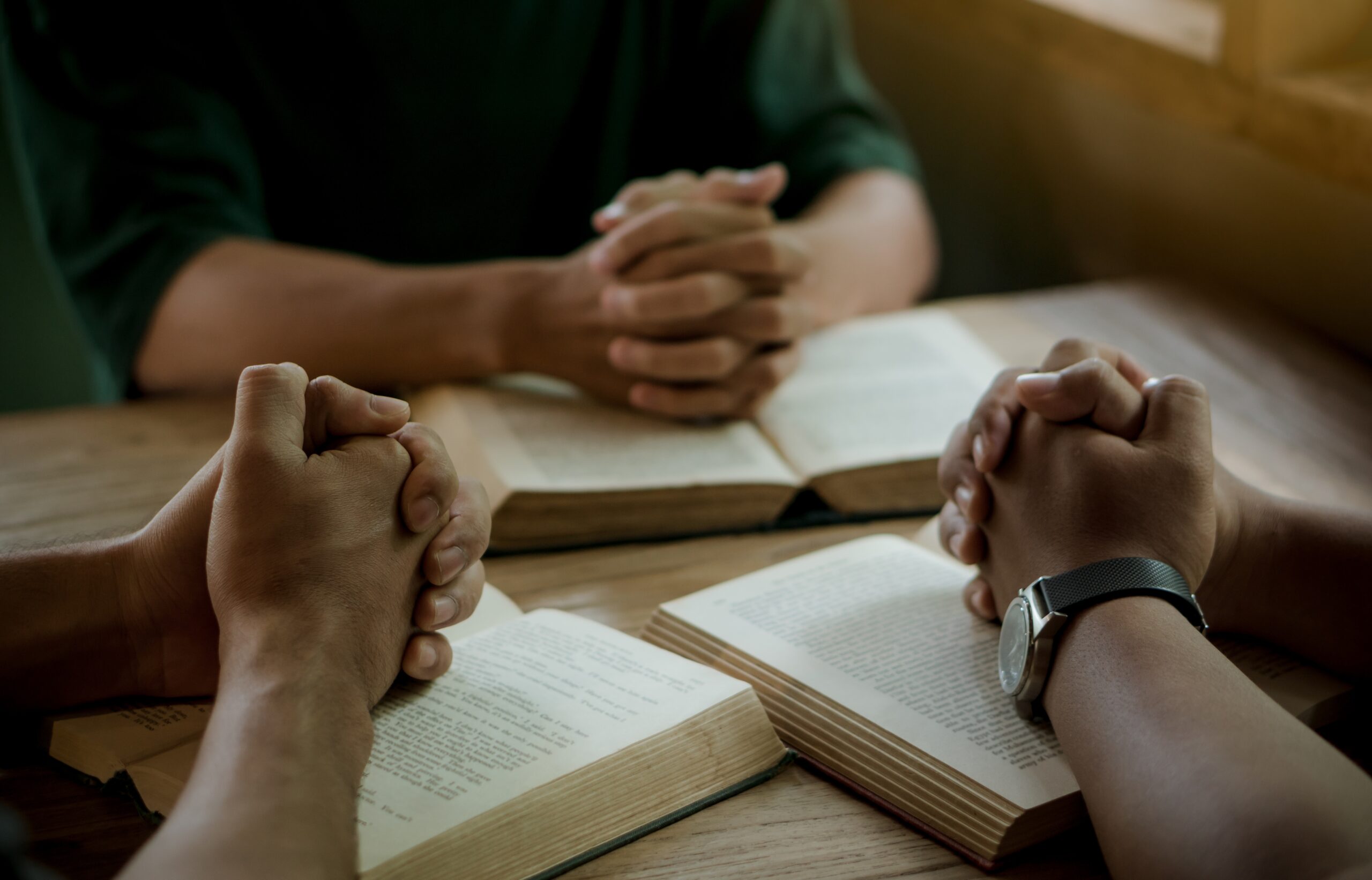 Group of christian people reading and study bible in home and pray together.Group of people holding hands praying worship god.Diverse religious shoot.